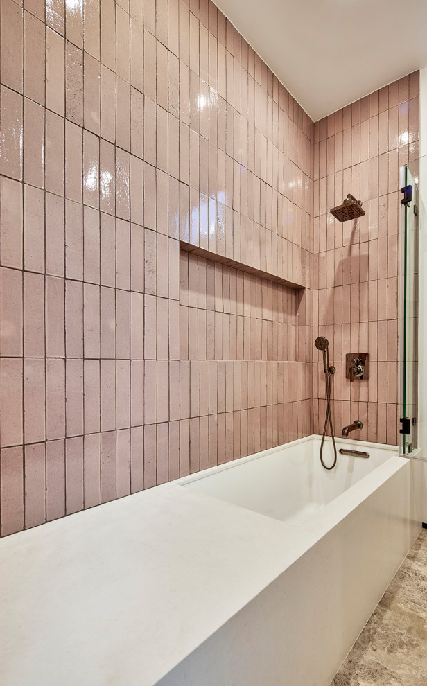 Photo of a mid-sized modern kids bathroom in Los Angeles with furniture-like cabinets, beige cabinets, a one-piece toilet, pink tile, ceramic tile, marble floors, an undermount sink, a hinged shower door, white benchtops, a floating vanity, an undermount tub, a shower/bathtub combo, pink walls, engineered quartz benchtops, a niche, a single vanity, brick walls and brown floor.