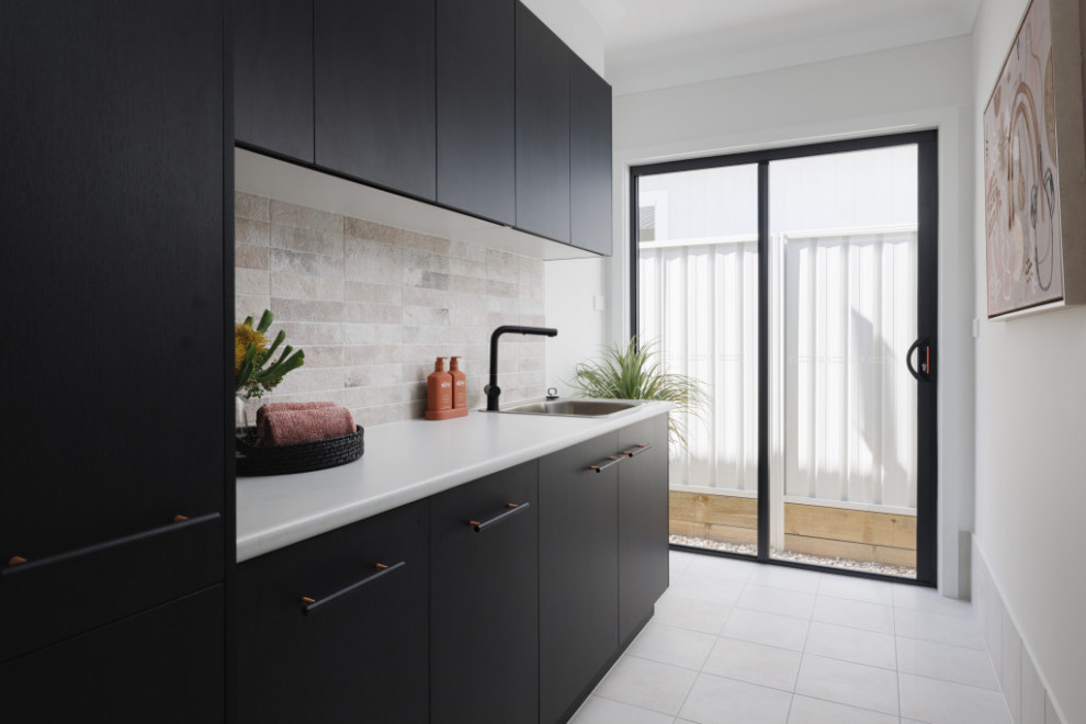 Inspiration for a contemporary single-wall dedicated laundry room in Wollongong with a single-bowl sink, black cabinets, laminate benchtops, multi-coloured splashback, ceramic splashback, ceramic floors, a stacked washer and dryer, grey floor and grey benchtop.