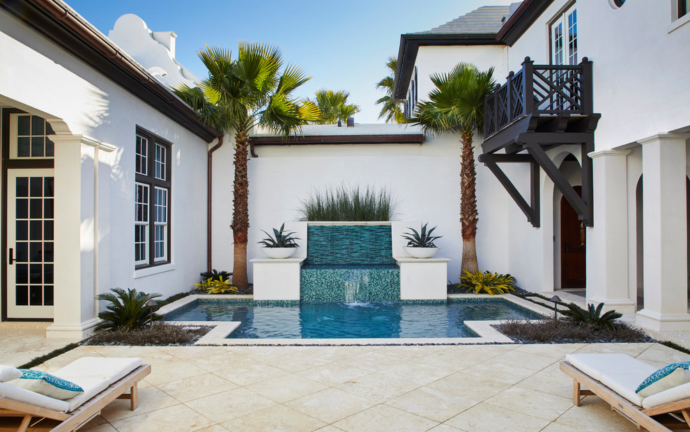 Tropical courtyard custom-shaped pool in Other with a water feature.