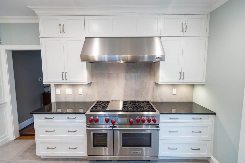 Open concept kitchen - large transitional galley ceramic tile and gray floor open concept kitchen idea in Bridgeport with an undermount sink, recessed-panel cabinets, white cabinets, granite countertops, gray backsplash, ceramic backsplash, stainless steel appliances, two islands and black countertops
