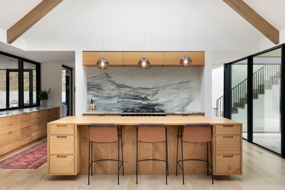 This is an example of a contemporary u-shaped open plan kitchen in Minneapolis with flat-panel cabinets, medium wood cabinets, marble benchtops, multi-coloured splashback, marble splashback, light hardwood floors, with island, beige floor, multi-coloured benchtop, exposed beam and vaulted.