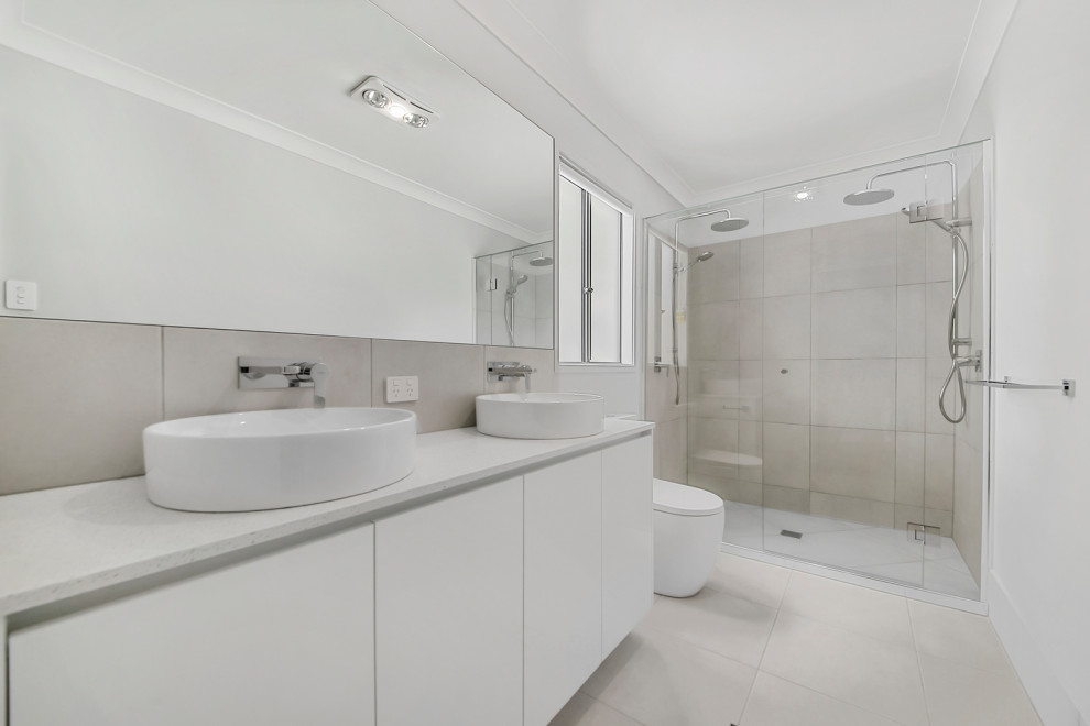 Design ideas for a mid-sized contemporary 3/4 bathroom in Brisbane with white cabinets, a double shower, a two-piece toilet, gray tile, white walls, porcelain floors, a drop-in sink, solid surface benchtops, white floor, a hinged shower door, white benchtops, a double vanity and a built-in vanity.