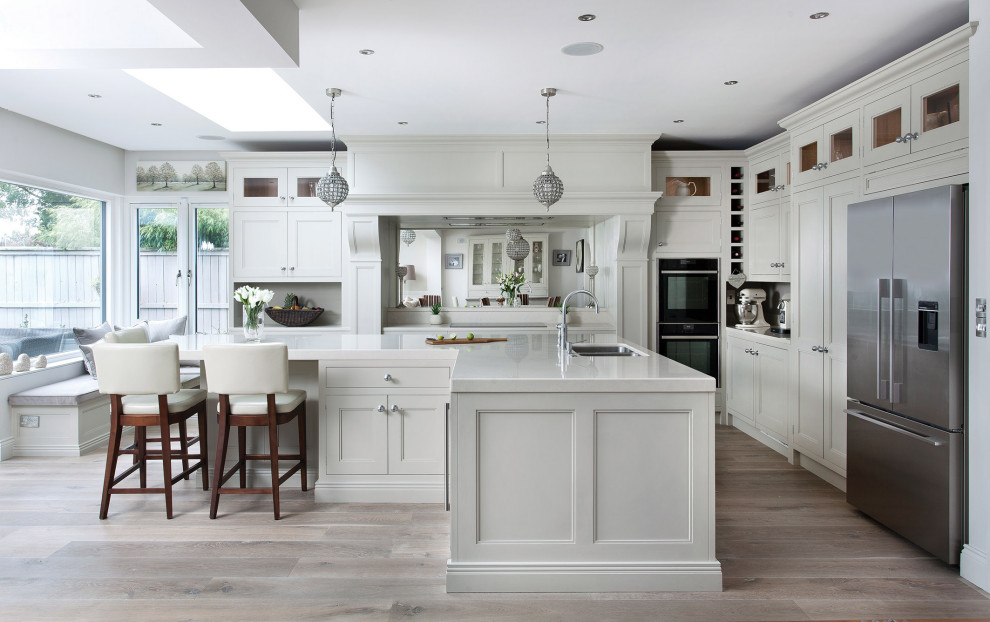 Inspiration for a large classic l-shaped kitchen/diner in Other with shaker cabinets, white cabinets, engineered stone countertops, black appliances, an island and white worktops.