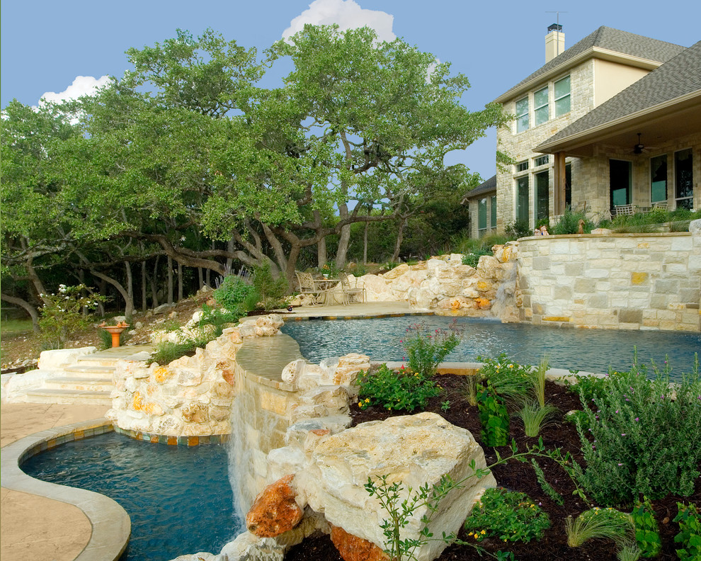 Photo of a large country backyard custom-shaped natural pool in Austin with a water feature and concrete slab.