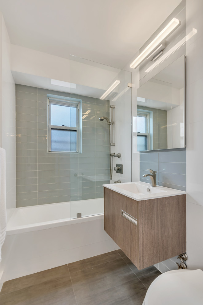 Design ideas for a small modern 3/4 bathroom in New York with flat-panel cabinets, brown cabinets, a drop-in tub, a shower/bathtub combo, a one-piece toilet, green tile, glass tile, grey walls, ceramic floors, a drop-in sink, quartzite benchtops, black floor and an open shower.