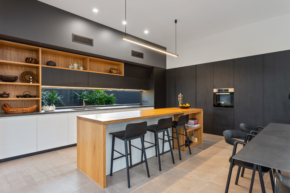 This is an example of a contemporary l-shaped eat-in kitchen in Gold Coast - Tweed with a double-bowl sink, flat-panel cabinets, black cabinets, wood benchtops, window splashback, with island, beige floor and brown benchtop.