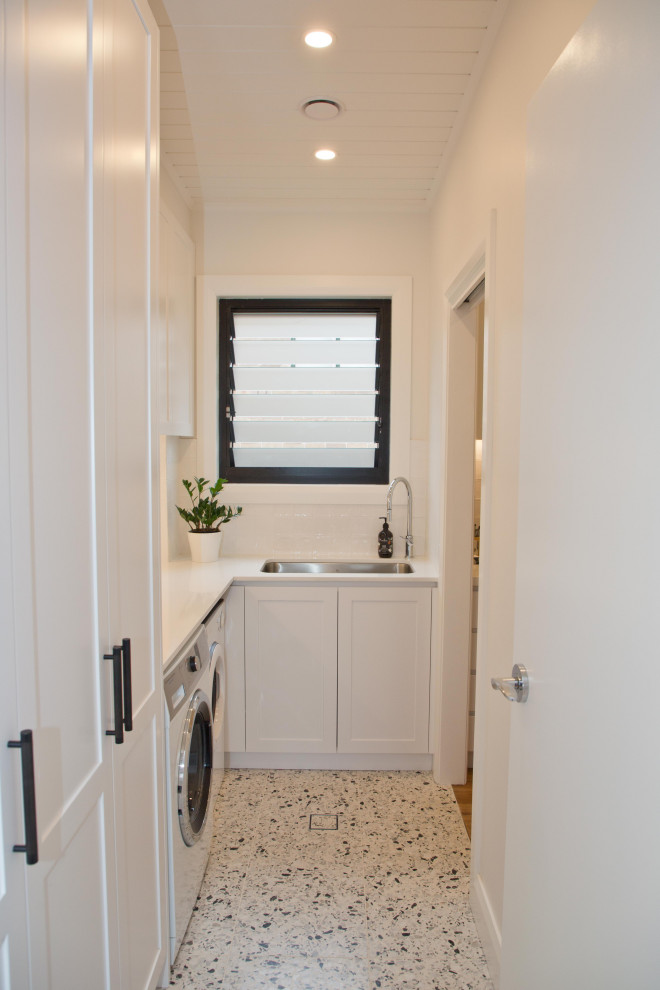 Small contemporary laundry room in Sydney with a drop-in sink, shaker cabinets, yellow cabinets, subway tile splashback, porcelain floors and white benchtop.