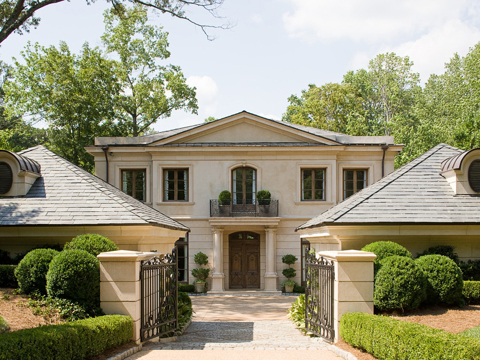 This is an example of a large traditional two-storey stucco beige exterior in Atlanta with a hip roof.