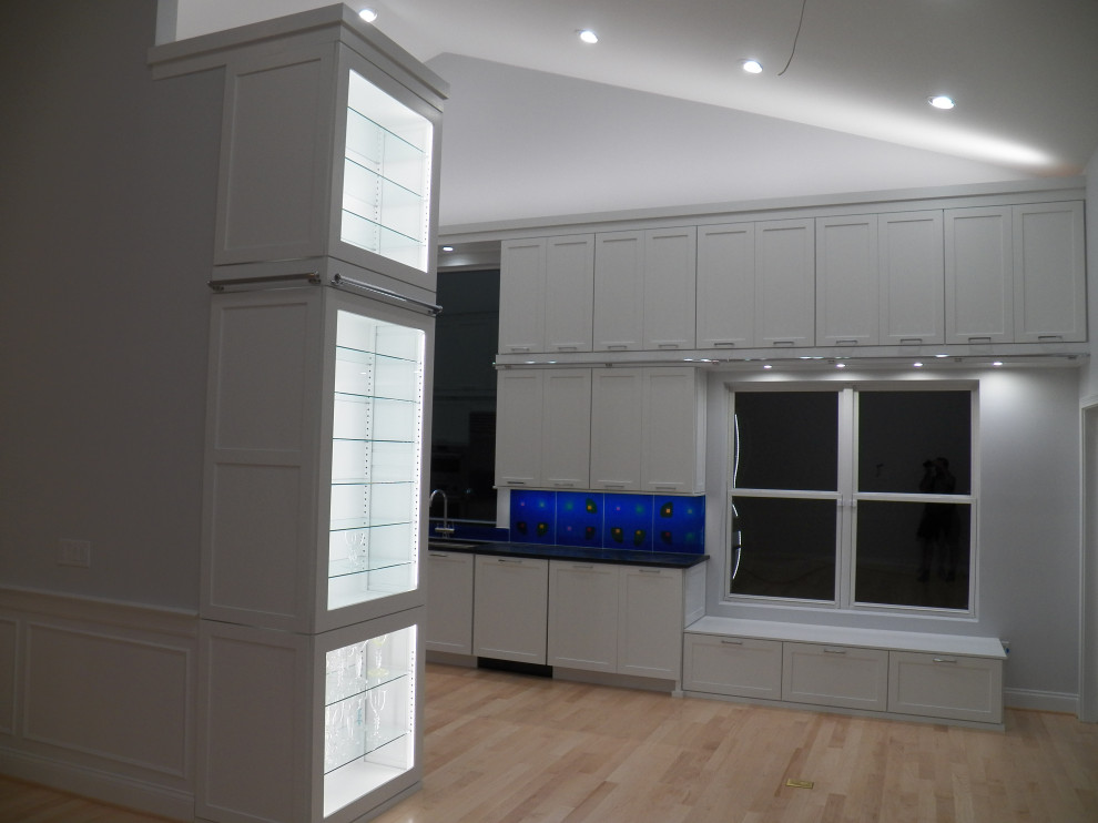 Design ideas for an expansive contemporary galley kitchen pantry in Cincinnati with an undermount sink, shaker cabinets, white cabinets, soapstone benchtops, blue splashback, glass tile splashback, stainless steel appliances, light hardwood floors, with island, black benchtop and vaulted.