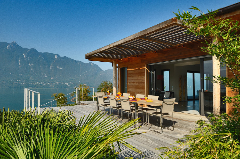 Photo of a large contemporary side yard deck in Grenoble with a pergola.
