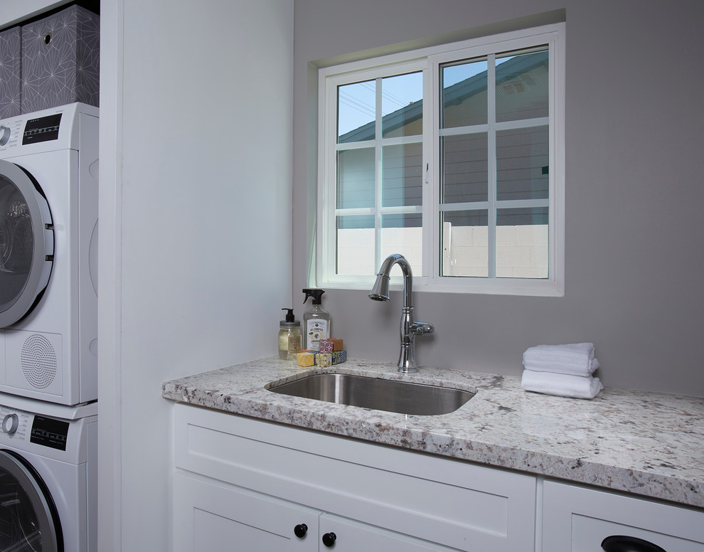 Inspiration for a mid-sized contemporary single-wall laundry closet remodel in Phoenix with a drop-in sink, shaker cabinets, white cabinets, granite countertops, gray walls and a stacked washer/dryer