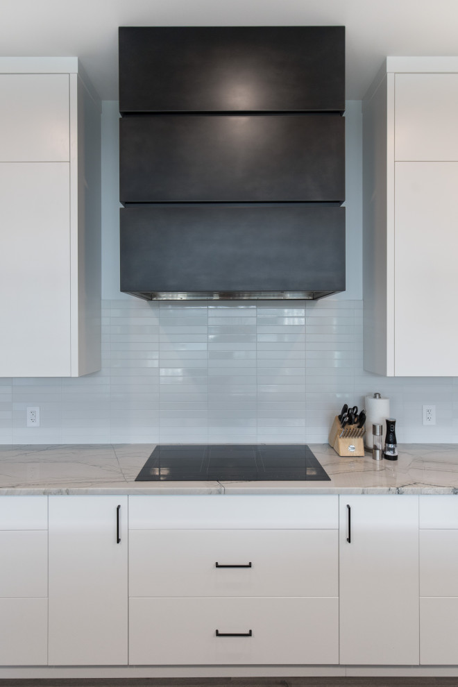 This is an example of a large traditional l-shaped kitchen pantry in Calgary with a submerged sink, flat-panel cabinets, white cabinets, quartz worktops, white splashback, matchstick tiled splashback, stainless steel appliances, dark hardwood flooring, an island, grey floors and white worktops.