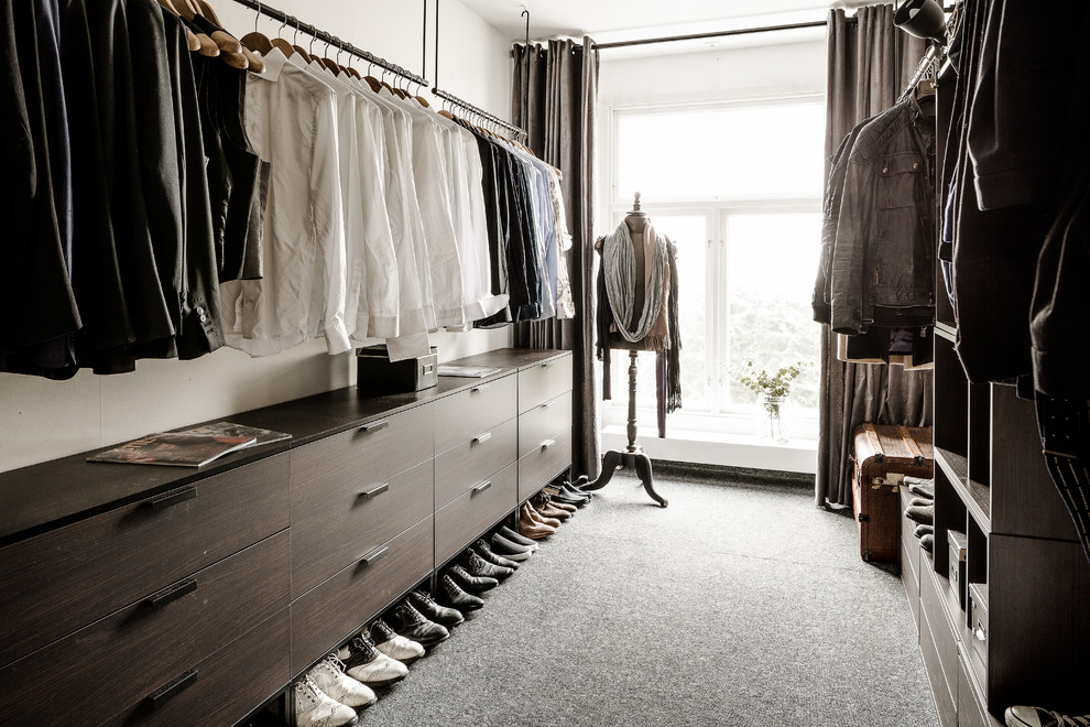 Design ideas for a mid-sized modern men's dressing room in Gothenburg with flat-panel cabinets, carpet, grey floor and dark wood cabinets.