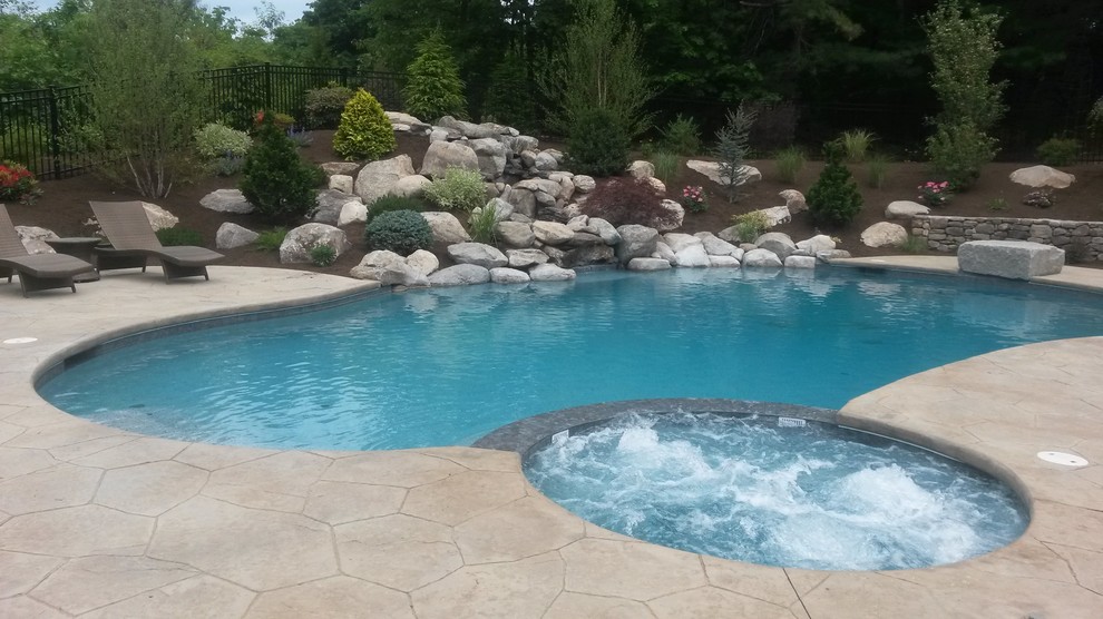 Expansive midcentury backyard round natural pool in Boston with a hot tub and stamped concrete.