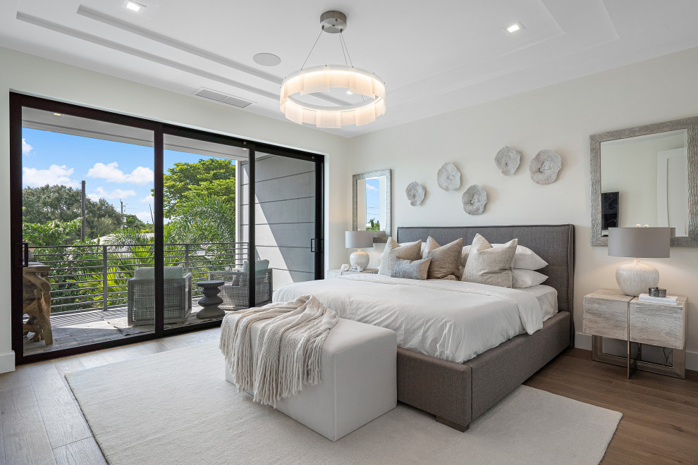 This is an example of a large contemporary master bedroom in Miami with beige walls, medium hardwood floors and beige floor.