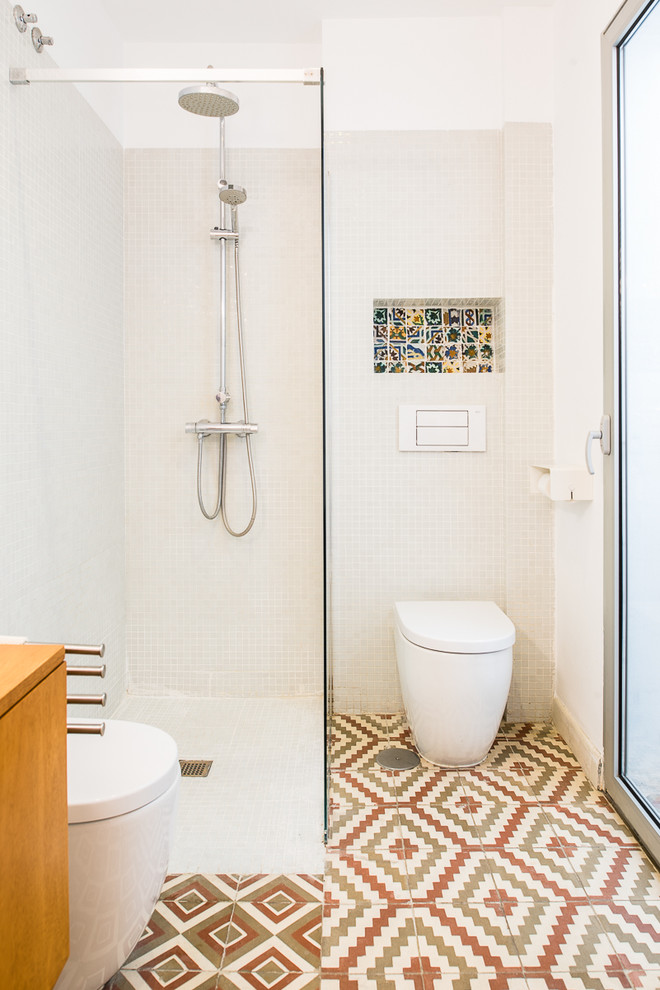 This is an example of a small eclectic 3/4 bathroom in Seville with a corner shower, a wall-mount toilet, white walls, ceramic floors and multi-coloured floor.