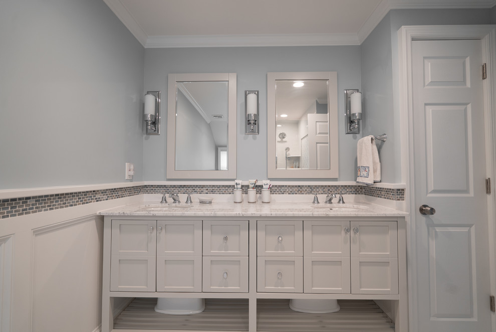 Design ideas for a mid-sized traditional kids bathroom in New York with shaker cabinets, white cabinets, a drop-in tub, a shower/bathtub combo, white tile, blue walls, porcelain floors, an undermount sink, marble benchtops, white floor and a sliding shower screen.