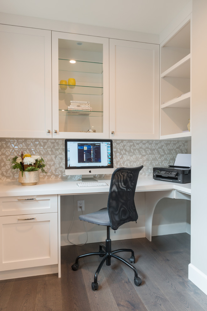 This is an example of a mid-sized modern home office in Vancouver with white walls, medium hardwood floors, a built-in desk and grey floor.