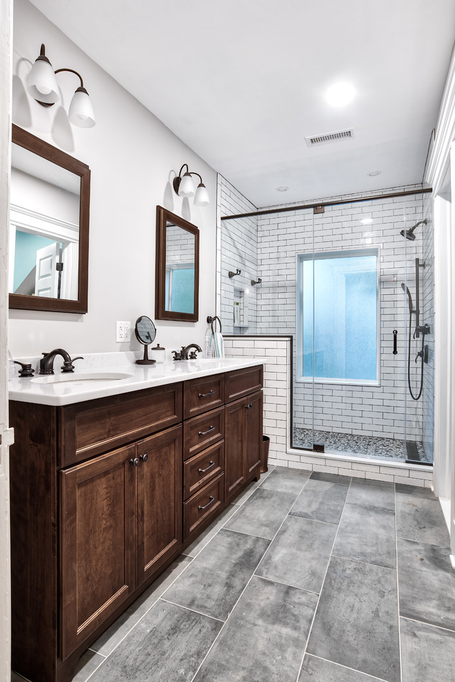 Photo of a large country master bathroom in New York with medium wood cabinets, white tile, subway tile, granite benchtops, white benchtops, an alcove shower, a two-piece toilet, a drop-in sink, a hinged shower door, grey walls, ceramic floors and grey floor.