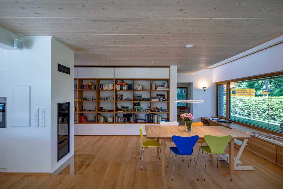 Inspiration pour une salle à manger ouverte sur le salon design avec un mur blanc, un sol en bois brun, un poêle à bois, un manteau de cheminée en plâtre et un plafond en bois.