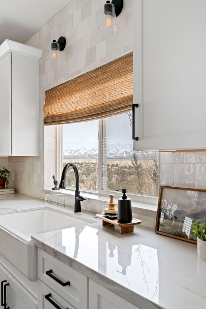 Example of a transitional vinyl floor and brown floor kitchen design with a farmhouse sink, shaker cabinets, white cabinets, quartzite countertops, white backsplash and stainless steel appliances