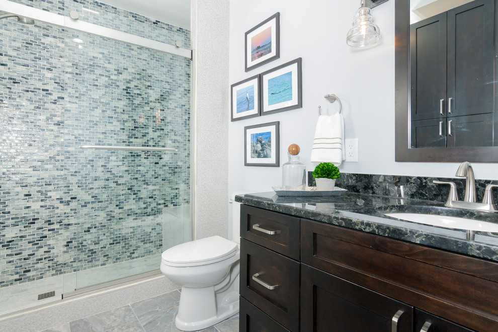 Inspiration for a mid-sized transitional 3/4 bathroom in DC Metro with shaker cabinets, medium wood cabinets, an alcove shower, a two-piece toilet, blue tile, matchstick tile, grey walls, porcelain floors, an undermount sink, granite benchtops, grey floor and a sliding shower screen.