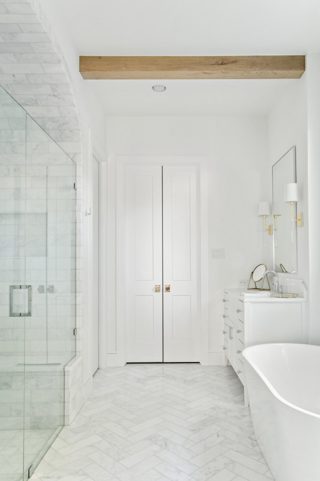 На фото: главная ванная комната в морском стиле с фасадами в стиле шейкер, синими фасадами, отдельно стоящей ванной, душем без бортиков, раздельным унитазом, белой плиткой, мраморной плиткой, белыми стенами, мраморным полом, врезной раковиной, мраморной столешницей, белым полом, душем с распашными дверями, серой столешницей, сиденьем для душа, тумбой под две раковины, встроенной тумбой и балками на потолке с