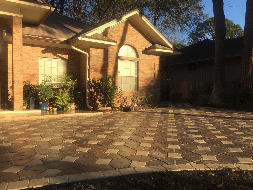 This is an example of a mid-sized traditional front yard driveway in Jacksonville with a container garden and brick pavers.