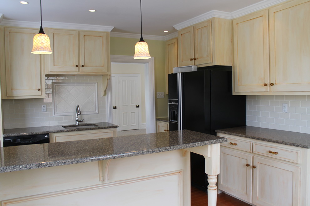 This is an example of a small traditional l-shaped separate kitchen in Philadelphia with an undermount sink, shaker cabinets, light wood cabinets, granite benchtops, grey splashback, stone tile splashback, black appliances, medium hardwood floors, a peninsula and brown floor.
