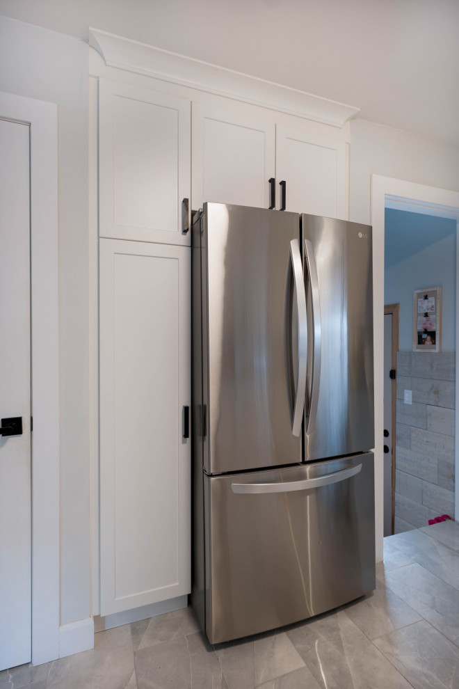 Inspiration for a small transitional l-shaped enclosed kitchen remodel with a double-bowl sink, shaker cabinets, white cabinets, quartz countertops, stainless steel appliances, no island and black countertops