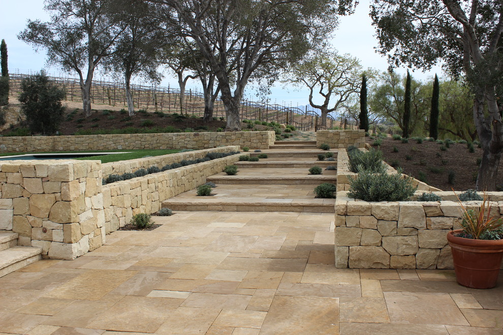Inspiration for an expansive mediterranean backyard patio in Los Angeles with a water feature, natural stone pavers and no cover.