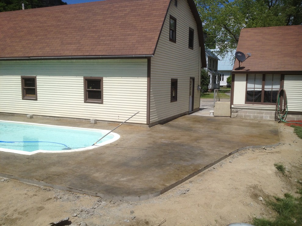 Design ideas for a mid-sized country backyard patio in Burlington with stamped concrete.