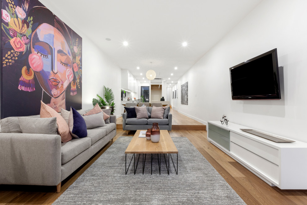 メルボルンにあるコンテンポラリースタイルのおしゃれなリビング (白い壁、無垢フローリング、壁掛け型テレビ、茶色い床) の写真