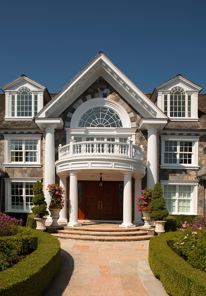 Photo of an expansive traditional three-storey white exterior in New York with stone veneer and a gable roof.