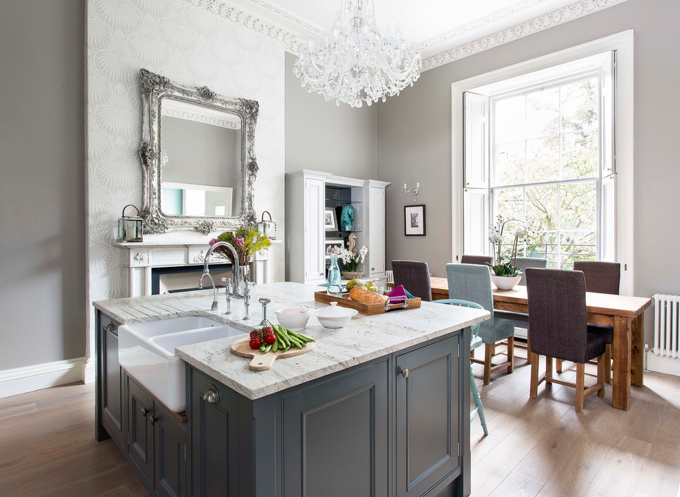 This is an example of a mid-sized traditional l-shaped eat-in kitchen in Edinburgh with an integrated sink, beaded inset cabinets, with island, medium hardwood floors, marble benchtops and grey cabinets.