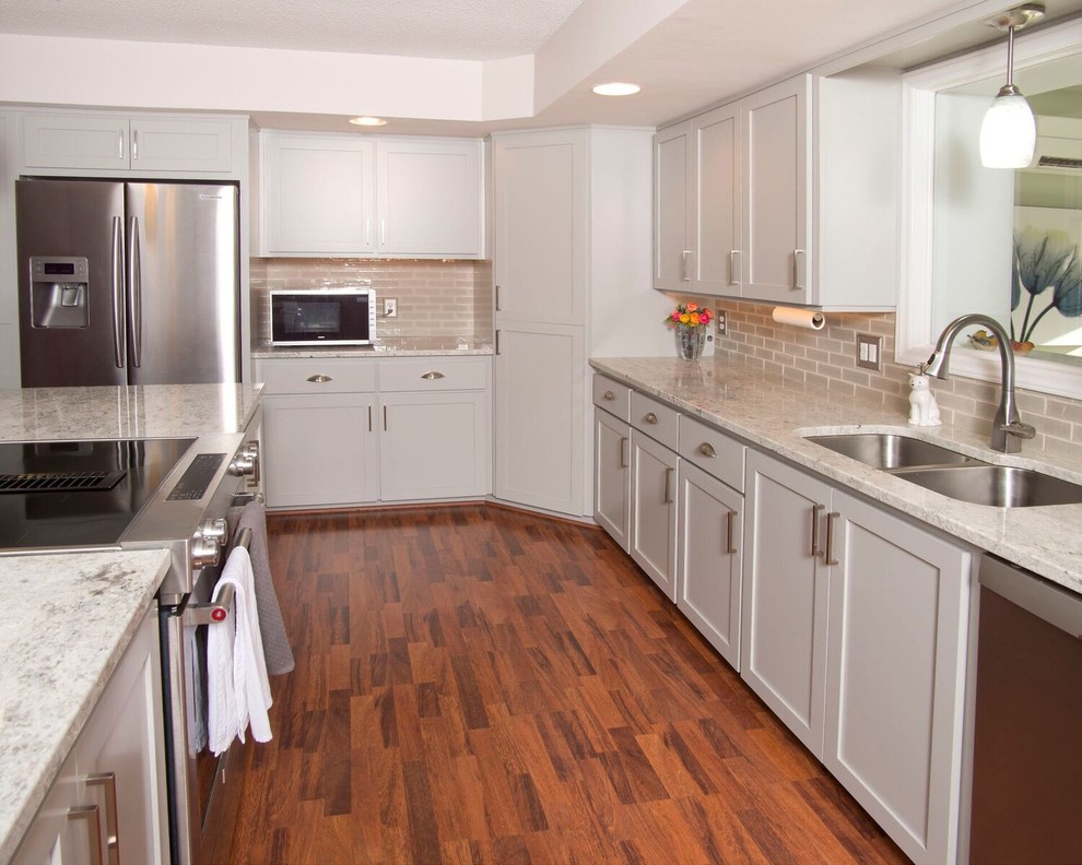 Inspiration for a mid-sized transitional u-shaped medium tone wood floor and brown floor eat-in kitchen remodel with a double-bowl sink, recessed-panel cabinets, gray cabinets, granite countertops, gray backsplash, subway tile backsplash, stainless steel appliances and an island