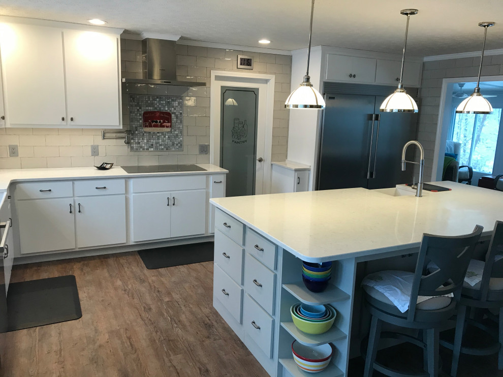 Example of a transitional medium tone wood floor kitchen design with flat-panel cabinets, white cabinets, quartzite countertops, ceramic backsplash and stainless steel appliances