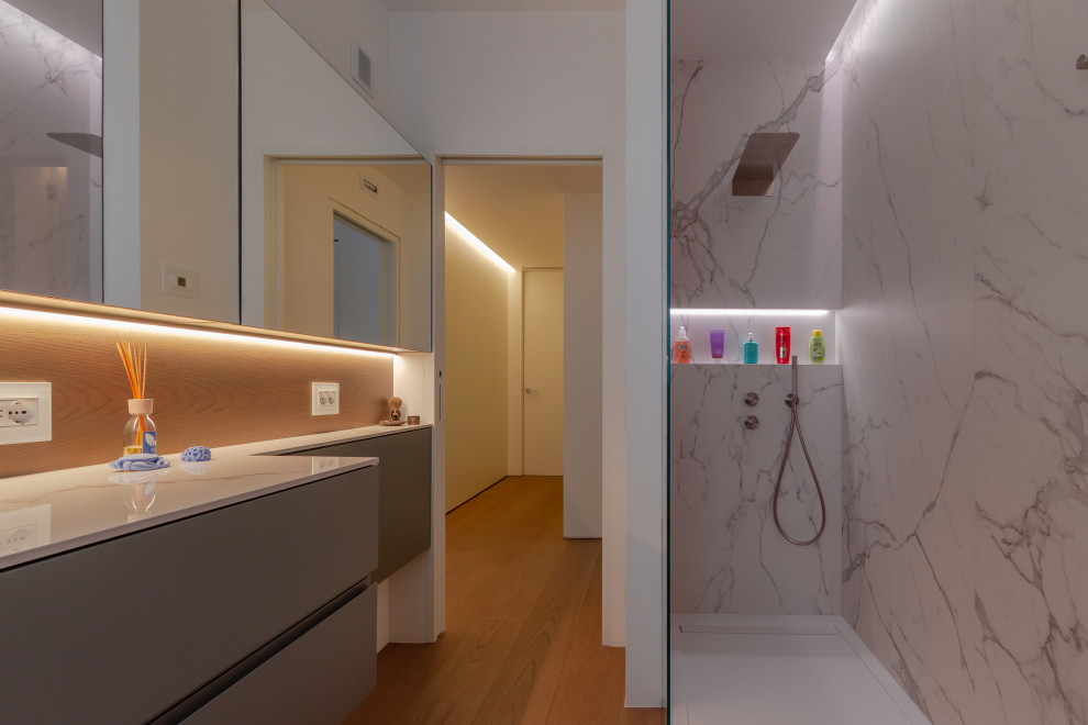 Modern inredning av ett mellanstort vit vitt badrum med dusch, med släta luckor, bruna skåp, en öppen dusch, en vägghängd toalettstol, vita väggar, målat trägolv, ett nedsänkt handfat, marmorbänkskiva, brunt golv och med dusch som är öppen