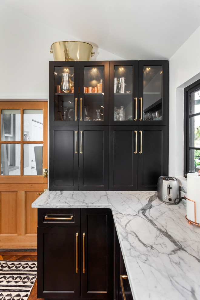 This is an example of a mid-sized contemporary l-shaped eat-in kitchen in Los Angeles with an undermount sink, shaker cabinets, black cabinets, marble benchtops, grey splashback, marble splashback, coloured appliances, linoleum floors, with island, brown floor and grey benchtop.
