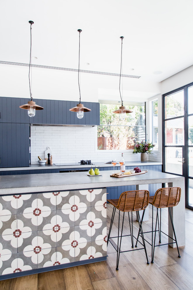 Inspiration for a contemporary l-shaped eat-in kitchen in Brisbane with flat-panel cabinets, blue cabinets, concrete benchtops, white splashback, subway tile splashback and with island.
