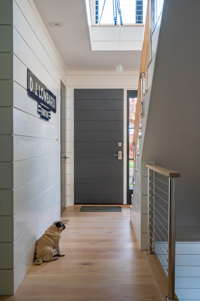This is an example of a mid-sized contemporary hallway in Boston with white walls, light hardwood floors and planked wall panelling.