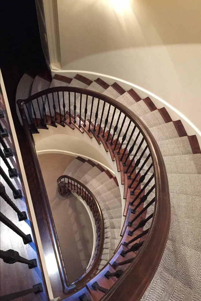 Photo of a large modern carpeted spiral staircase in Chicago with carpet risers and metal railing.