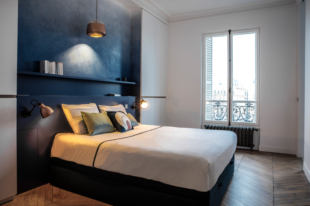 Large contemporary master bedroom in Paris with blue walls and light hardwood floors.