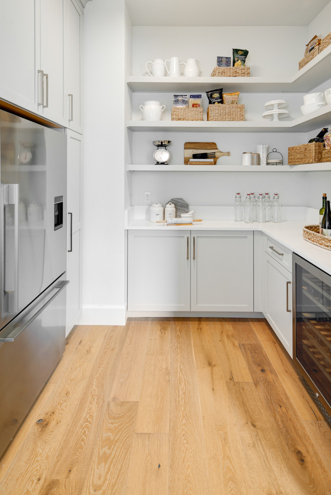 Design ideas for a transitional u-shaped kitchen in Portland with shaker cabinets, grey cabinets, stainless steel appliances, medium hardwood floors, no island, brown floor and white benchtop.