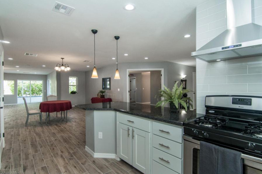 Example of a mid-sized u-shaped open concept kitchen design in Phoenix with recessed-panel cabinets, white cabinets, gray backsplash, subway tile backsplash, stainless steel appliances and no island