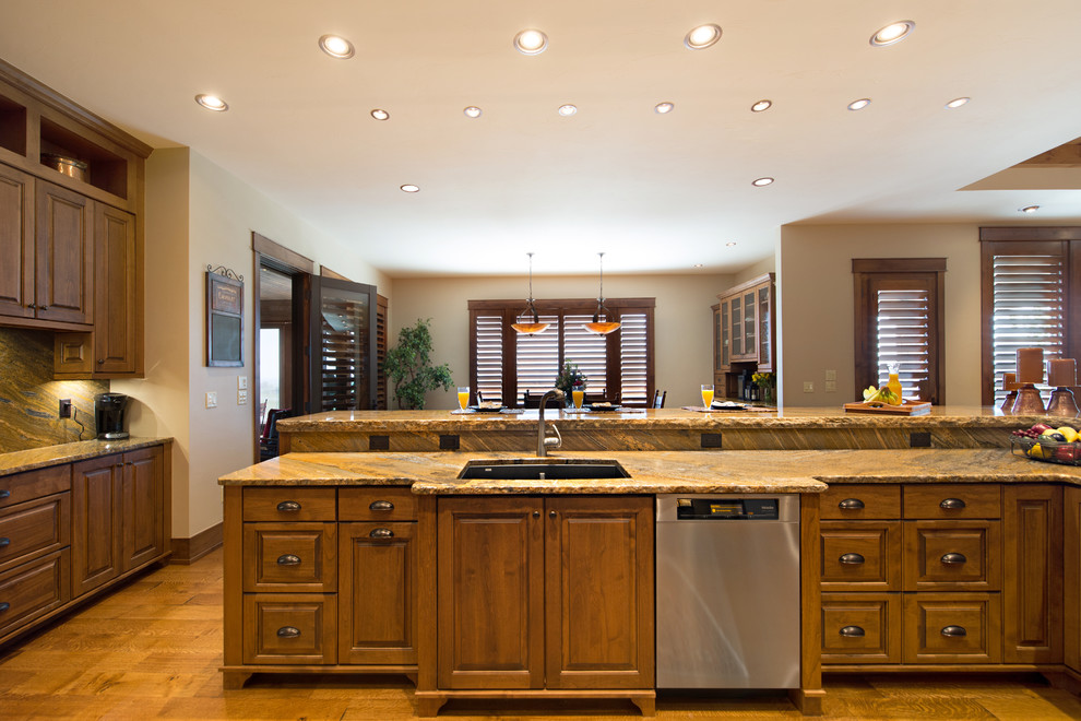 This is an example of an expansive arts and crafts l-shaped open plan kitchen in Denver with an undermount sink, recessed-panel cabinets, medium wood cabinets, granite benchtops, multi-coloured splashback, stone slab splashback, stainless steel appliances, medium hardwood floors and a peninsula.