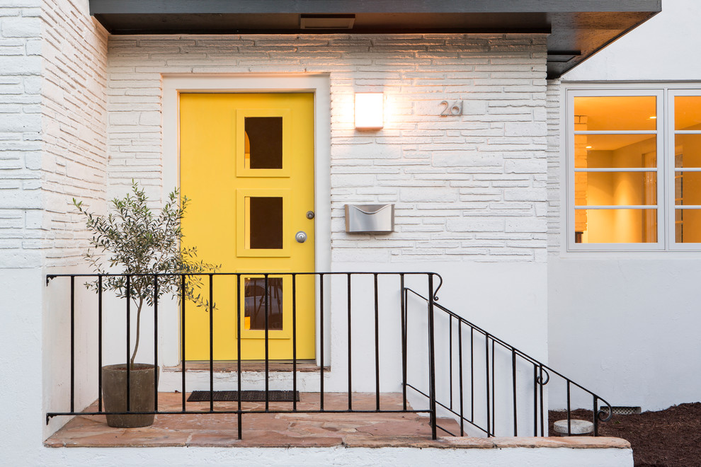 This is an example of a midcentury front door in Charleston with white walls, slate floors, a single front door and a yellow front door.
