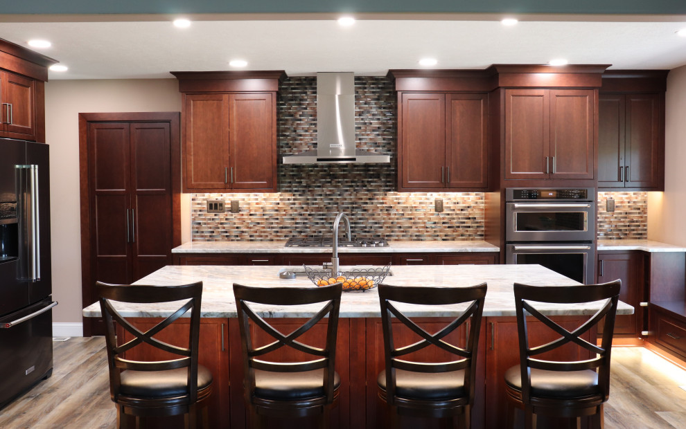 Inspiration for a large transitional l-shaped enclosed kitchen remodel with an undermount sink, beaded inset cabinets, granite countertops, multicolored backsplash, an island and beige countertops