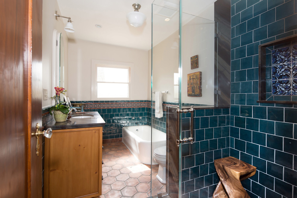 This is an example of a mid-sized mediterranean master bathroom in Los Angeles with an undermount sink, shaker cabinets, medium wood cabinets, quartzite benchtops, a corner tub, a corner shower, a one-piece toilet, blue tile, ceramic tile, white walls and terra-cotta floors.