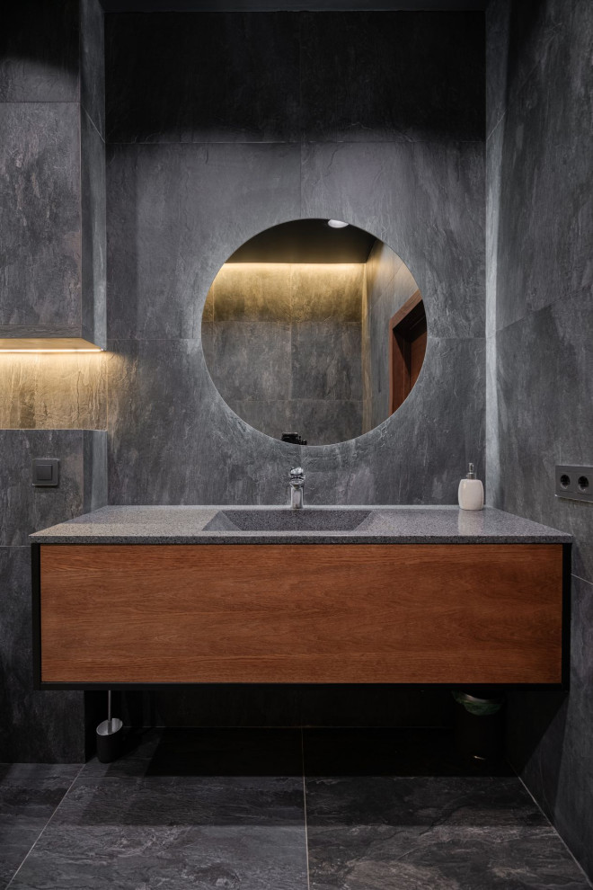 Свежая идея для дизайна: большая ванная комната в современном стиле с фасадами цвета дерева среднего тона, отдельно стоящей ванной, угловым душем, раздельным унитазом, серой плиткой, керамогранитной плиткой, серыми стенами, полом из керамогранита, душевой кабиной, врезной раковиной, столешницей из искусственного камня, серым полом, душем с распашными дверями, серой столешницей, зеркалом с подсветкой, тумбой под одну раковину и подвесной тумбой - отличное фото интерьера